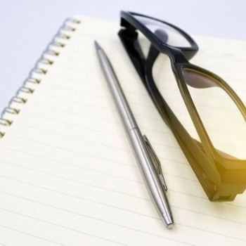 notebook page with nerd glasses on it with a silver pen on left side