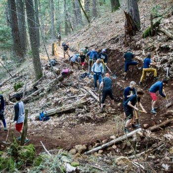 people with shovels working on bike trail in the woods