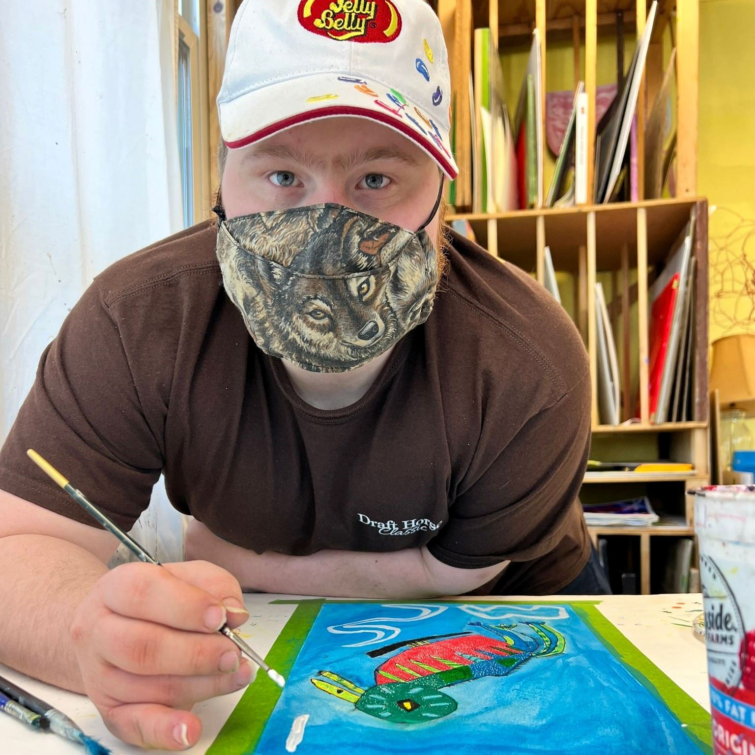 A young person wearing a mask works on a painting at NCA
