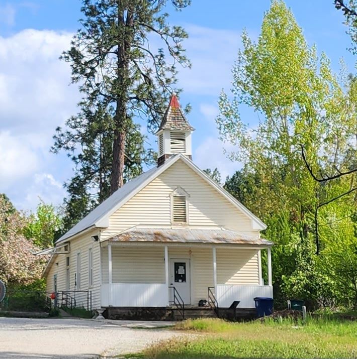 An old white school house with a steeple.