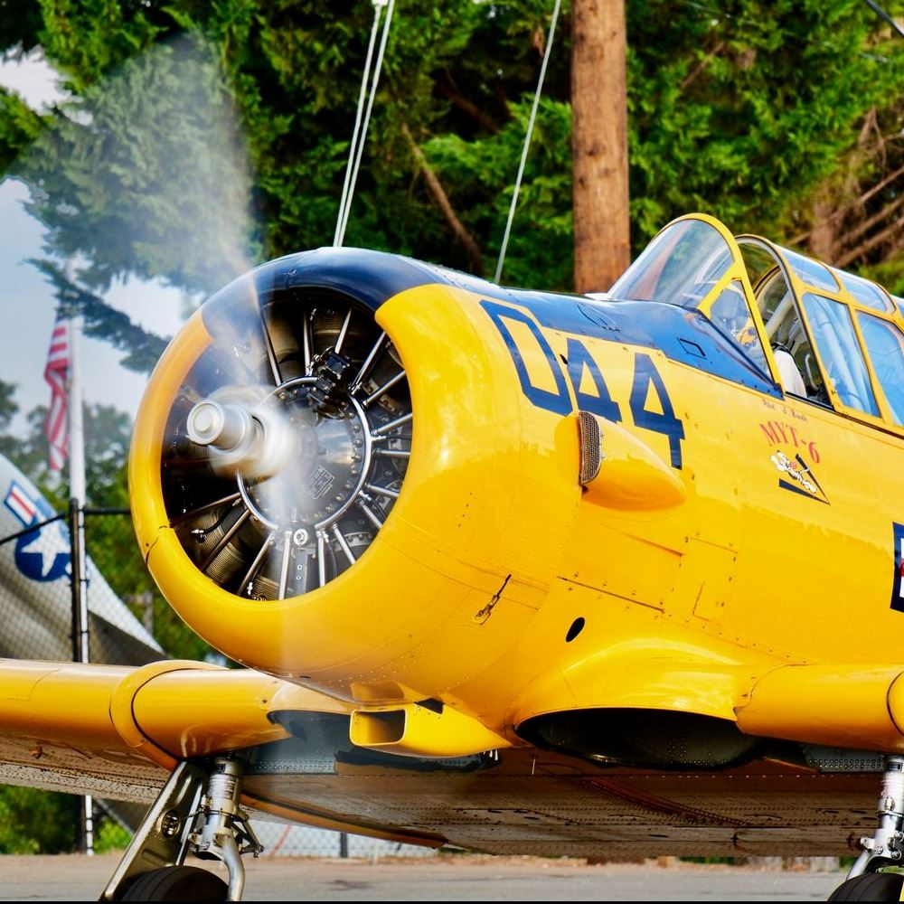 A bright yellow plane with a spinning proeller takes off from the runway of the Nevada County airpor