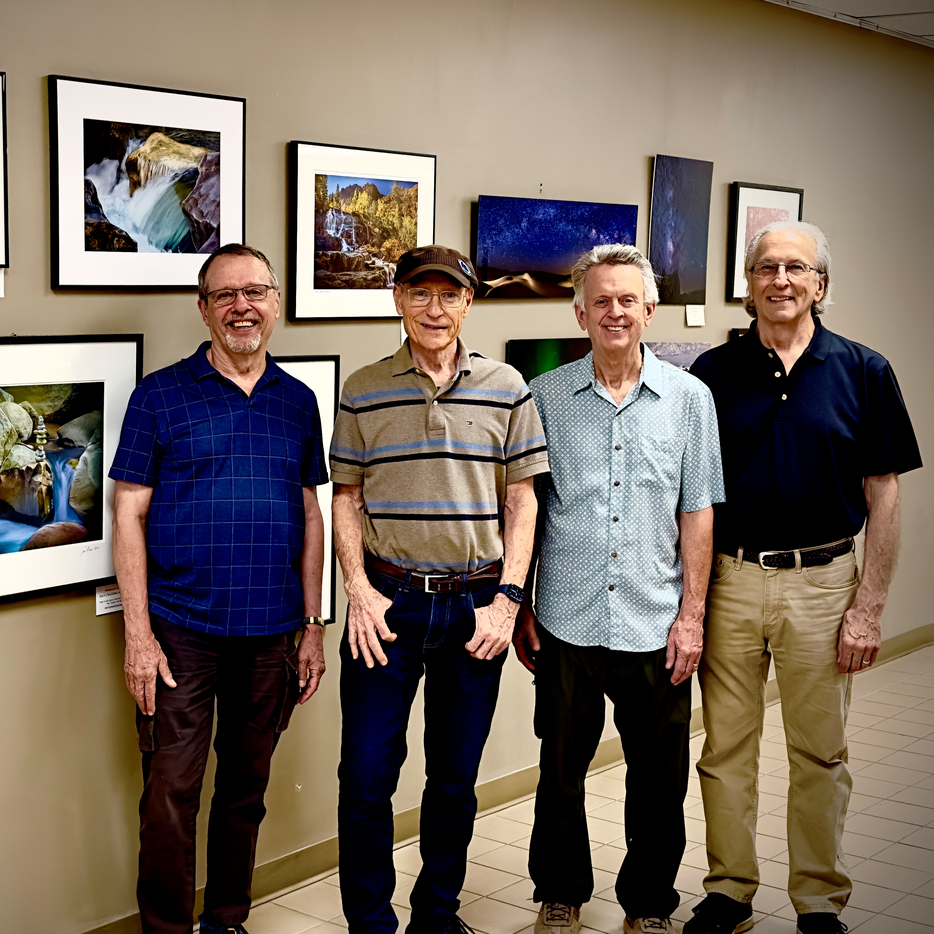 A group of people stand in front of a wall of photographs