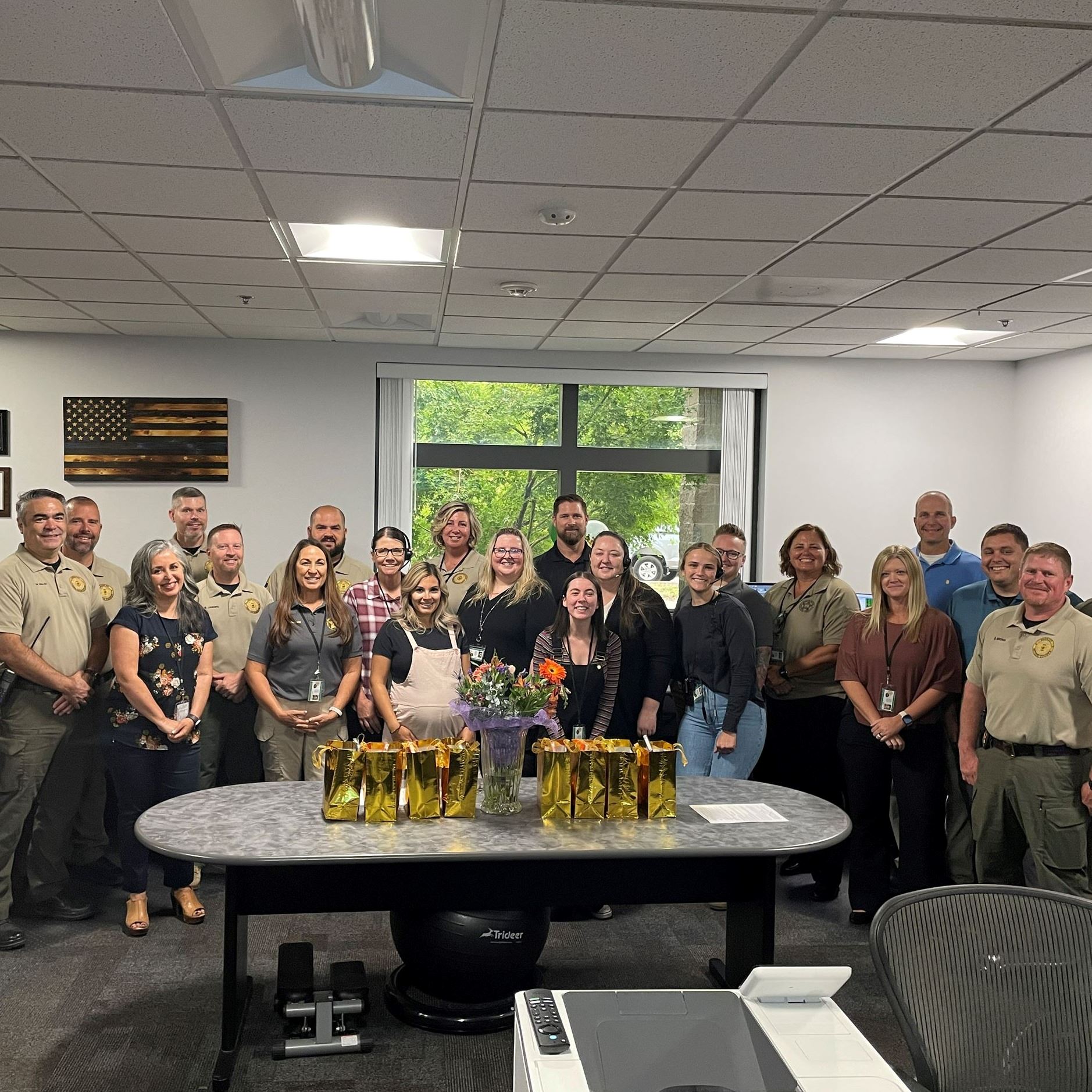 A large group of people pose in front of a picture window at the Regional Dispatch Center